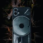 A close-up of a transparent smartphone placed on a forest floor. Modern technology meets nature's beauty.