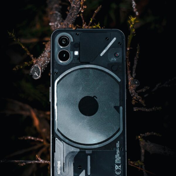 A close-up of a transparent smartphone placed on a forest floor. Modern technology meets nature's beauty.